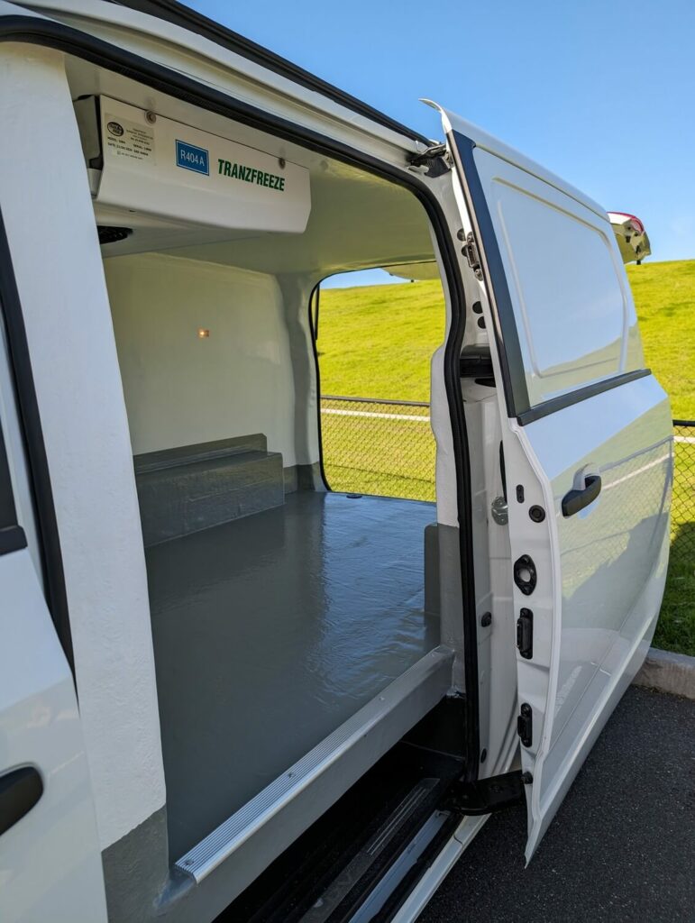 Refrigerated van side door open showing insulated walls and a sealed floor