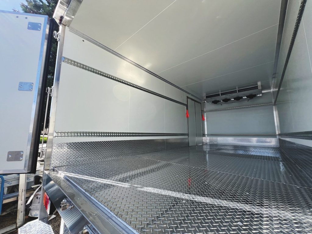 Inside a Tranzfreeze refrigerated truck body showing insulated fibreglass panels, checker-plate floor, and roof-mounted evaporator